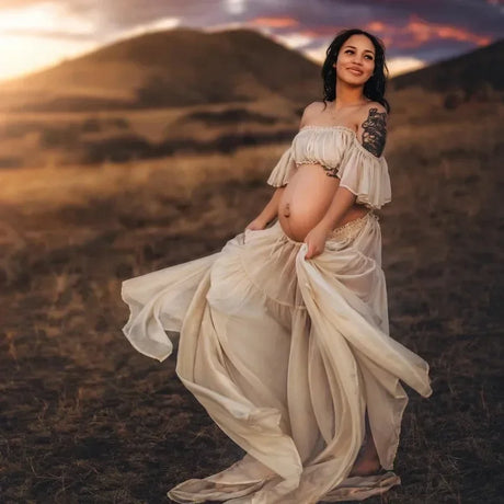 Pregnant woman in a Boho two-piece maternity set, flowing dress, outdoors at sunset for a photoshoot.