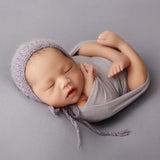 Newborn sleeping peacefully wrapped in soft blanket with knitted cap, perfect for photography and cozy comfort.