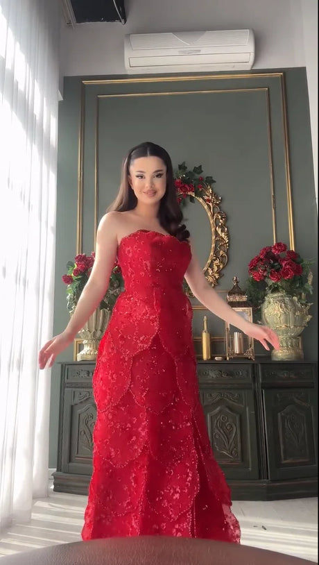Model showcasing a stunning strapless red engagement dress with intricate lace and beading details.