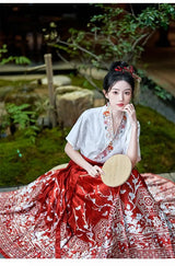 Traditional Hanfu oversized embroidered blouse with red skirt, elegantly styled in a serene outdoor setting.