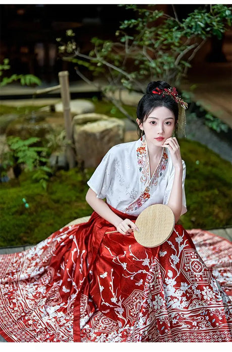 Traditional Hanfu oversized embroidered blouse with red skirt, elegantly styled in a serene outdoor setting.