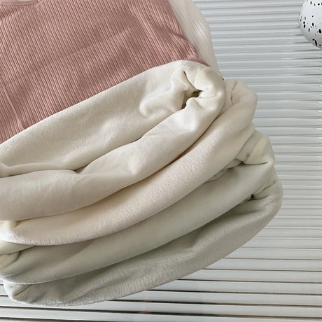 Folded casual velvet crop tank in cream and blush colors, showcasing sleek and comfortable fabric texture.