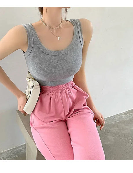 Model wearing a gray sleeveless ribbed tank top with pink sweatpants, showcasing a casual streetwear style.