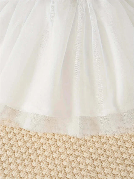 Close-up of a white tulle skirt detail on a textured beige background, perfect for newborn girls' summer dresses.