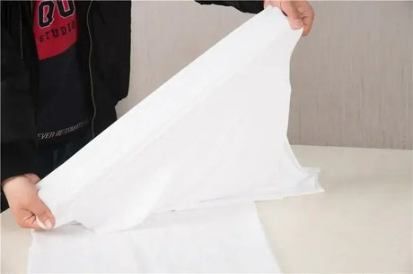 Folded white polyester blanket being prepared for a baby photo shoot backdrop, suitable for unisex infants.