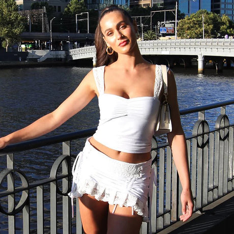 Model wearing Lace Strap Pleated Camisole Tank Top with a stylish white skirt by the river in summer.