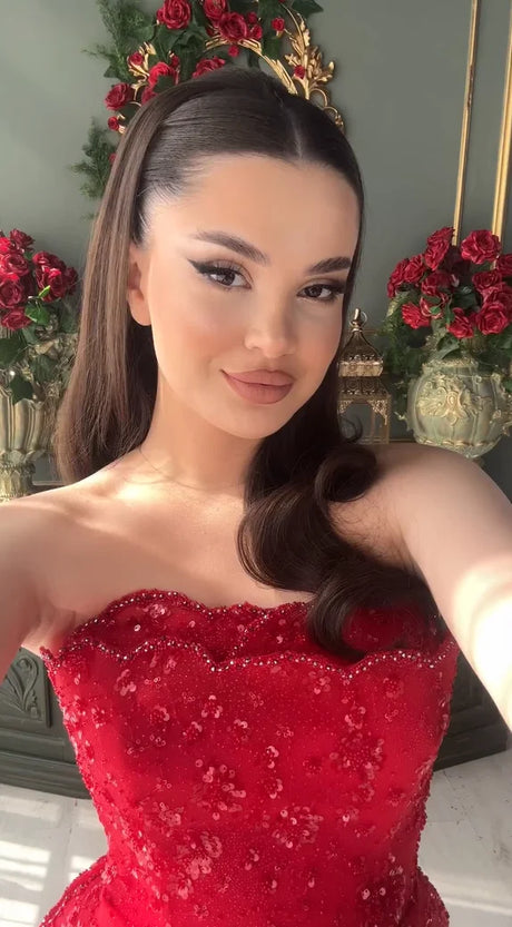 Selfie of a woman in a sparkly red strapless dress with long hair, surrounded by festive decorations.