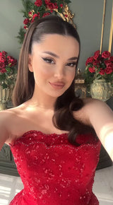 Selfie of a woman in a stunning red strapless gown, showcasing elegant beading and glamorous makeup.