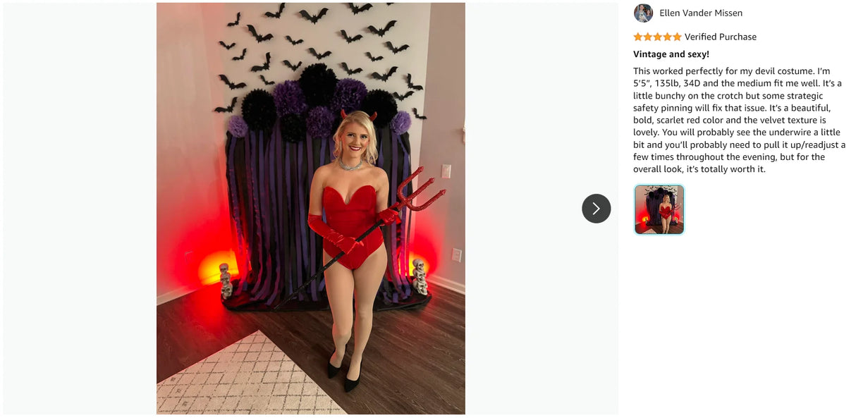 Woman in vintage devil costume with red gloves and heart-shaped top in festive Halloween setting.