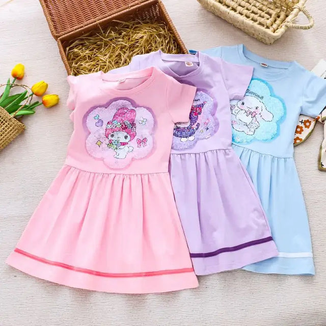 Three cute knee-length summer dresses for girls in pink, purple, and blue with cartoon designs, perfect for ages 4-6.