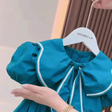 Cute blue baby girl's dress with puff sleeves and Peter Pan collar, displayed on a hanger.