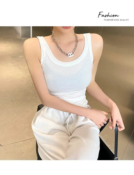 Model wearing a white RetroRib™ 90s vintage ribbed tank top, paired with casual white pants and a silver necklace.