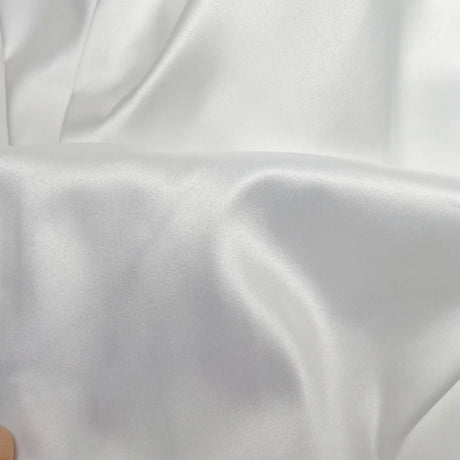Close-up of luxurious white satin fabric, ideal for bridal gowns and elegant dresses.