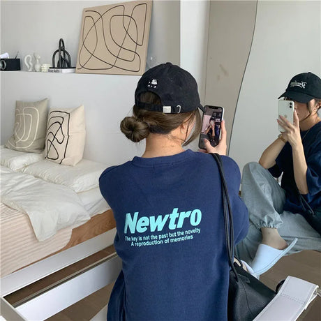 A person wearing an oversized navy Newtro streetwear tee, reflecting a relaxed urban style.