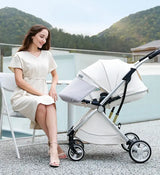 Woman sitting beside a foldable twin baby stroller outdoors with mountains in the background.