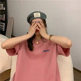 Woman wearing a pink oversized Harajuku streetwear tee with Newtro print and a gray beret, posing playfully indoors.