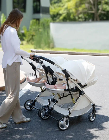 Mother pushing a foldable twin baby stroller on a sunny day, featuring sleek design and comfortable seating for infants.