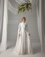 Elegant Muslim wedding dress with pearls, high neck, long sleeves, and floor-length satin skirt.