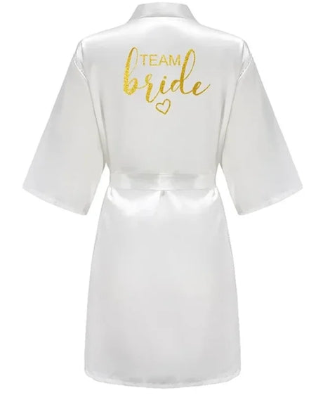 White satin kimono robe with 'TEAM BRIDE' in gold lettering, perfect for bridal parties.