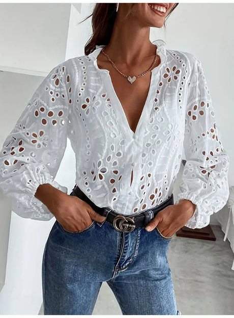Elegant hollow out white lace shirt with long sleeves, styled with jeans and a belt, perfect for summer.