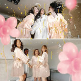 Bridesmaids celebrating in knee-length satin robes during a joyful event with balloons and confetti.