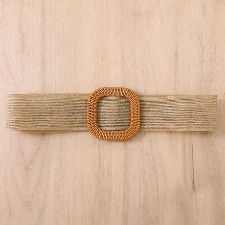 Natural woven belt with square wooden buckle on light wooden background.