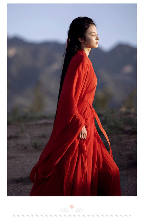 Elegant woman in a flowing red Hanfu dress against a scenic backdrop, showcasing traditional Chinese cosplay costume.