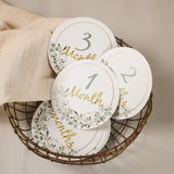 Set of baby milestone cards in a basket, featuring months 1 to 3 with floral designs, ideal for newborn photography.