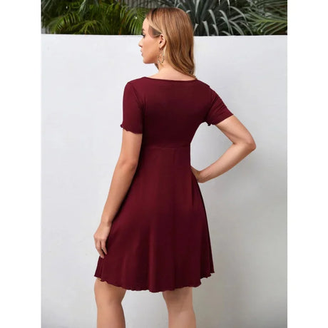 Back view of a woman in a burgundy knee-length V-neck maternity dress perfect for summer.