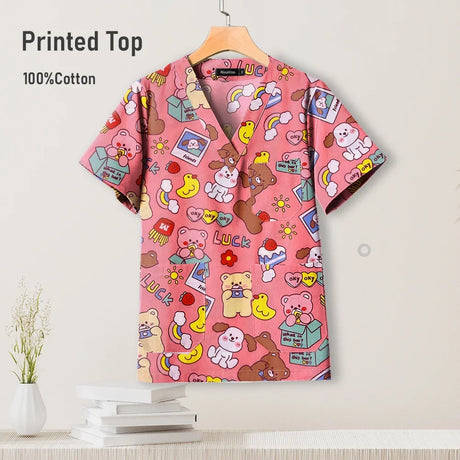 Cute printed pediatric nursing scrub top in pink, 100% cotton, featuring playful designs for healthcare professionals.