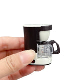 Miniature coffee maker prop held in hand, perfect for newborn baby photography setups with unisex design.