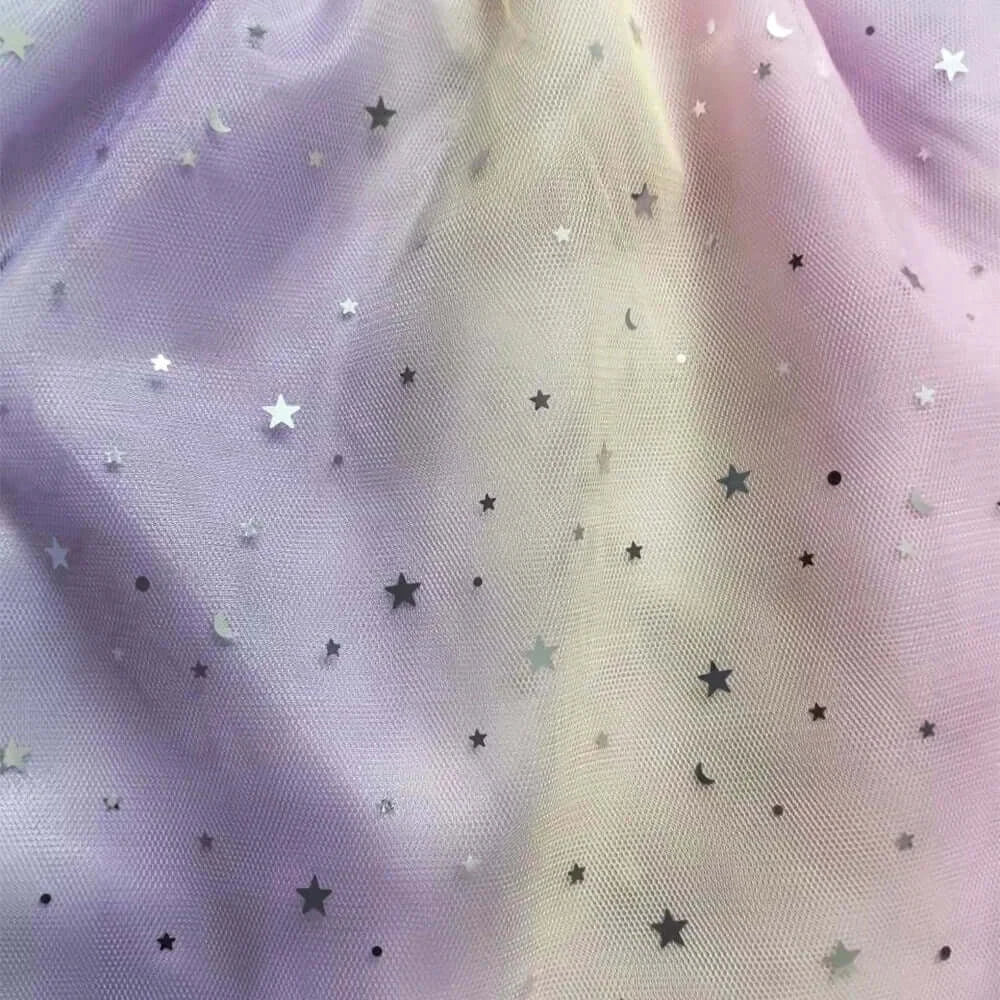 Close-up of shimmering star-patterned mesh fabric in pastel purple and cream colors for children's dress.