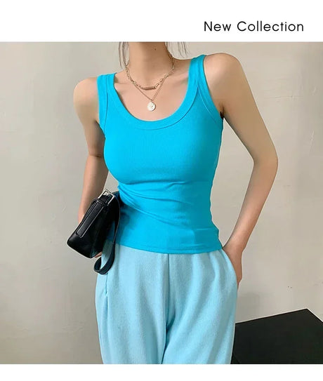 Woman wearing a sleeveless turquoise ribbed tank top with a stylish black handbag, showcasing a new collection.