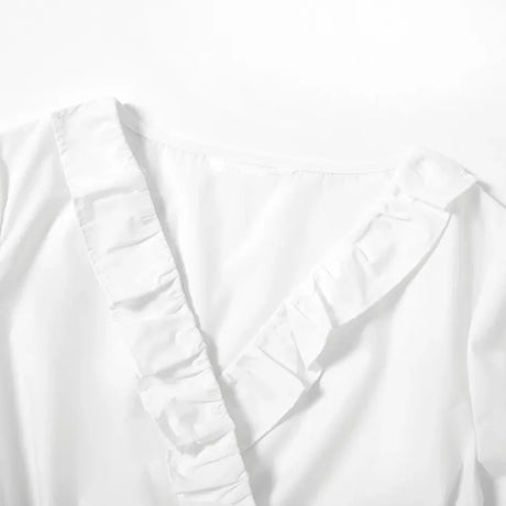 Close-up of a V-neck maternity dress with ruffled detailing in white cotton fabric.