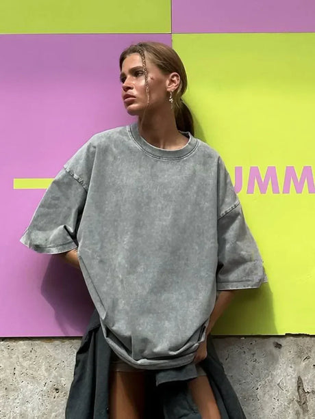 Woman wearing a loose gray casual t-shirt against a colorful background, showcasing modern street style.
