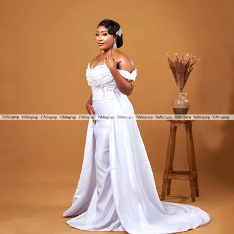 Elegant off-shoulder wedding dress with detachable train and pearl details, perfect for bridal elegance.