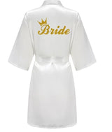 Elegant white satin robe with 'Bride' in gold glitter on the back, perfect for wedding celebrations.