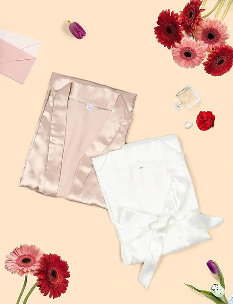 7-piece satin bride robe set in blush and white on a floral background, perfect for bridal party gifts.