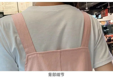 Back view of a woman wearing a pink strap dress over a white t-shirt, showcasing casual style.