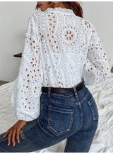 Back view of a woman wearing a hollow-out white lace shirt with long sleeves and jeans, showcasing elegant summer style.