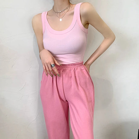 Model wearing a pink sleeveless ribbed tank top with a casual outfit, showcasing streetwear style.