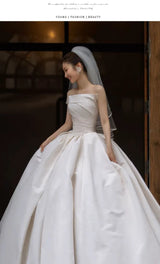 Elegant bride in a strapless white satin wedding dress, showcasing timeless beauty and fashion. Perfect for bridal occasions.