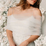 Model wearing a sheer white bridal bolero over an elegant wedding dress, showcasing delicate style and sophistication.