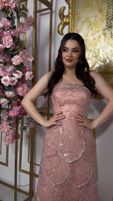 Customized pink beaded engagement dress with tiered design, showcased in an elegant setting with floral decor.