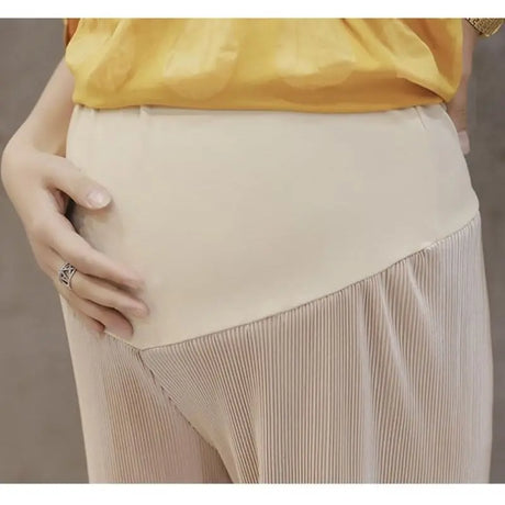Close-up of a woman wearing breathable adjustable waist maternity pants in summer, showcasing pleated design and comfort for expecting mothers.