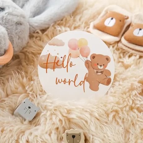Cute bear milestone card saying 'Hello World' with balloons, perfect for baby photo shoots and celebrations.