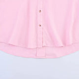 Close-up of a pink oversized button-up shirt, showcasing its soft fabric and curved hemline.