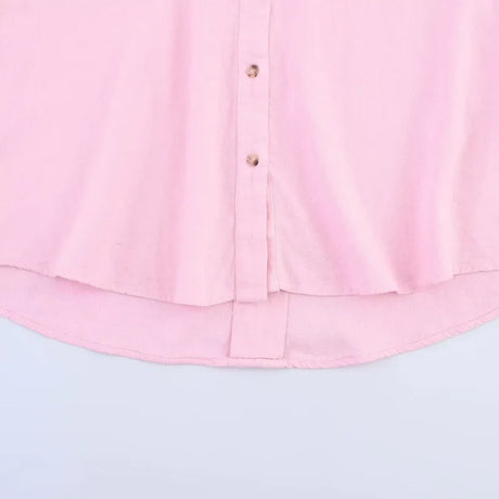 Close-up of a pink oversized button-up shirt, showcasing its soft fabric and curved hemline.