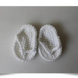 White baby slippers with a cozy knitted texture, perfect for keeping little feet warm and stylish.
