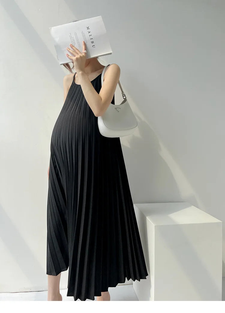 Stylish pregnant woman wearing a pleated black maternity dress, showcasing comfort and elegance for summer.
